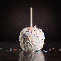 Birthday cake caramel apple topped with white chocolate drizzle and colorful sprinkles