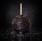 Dark chocolate sea salt gourmet caramel apple with chocolate drizzle on a black background